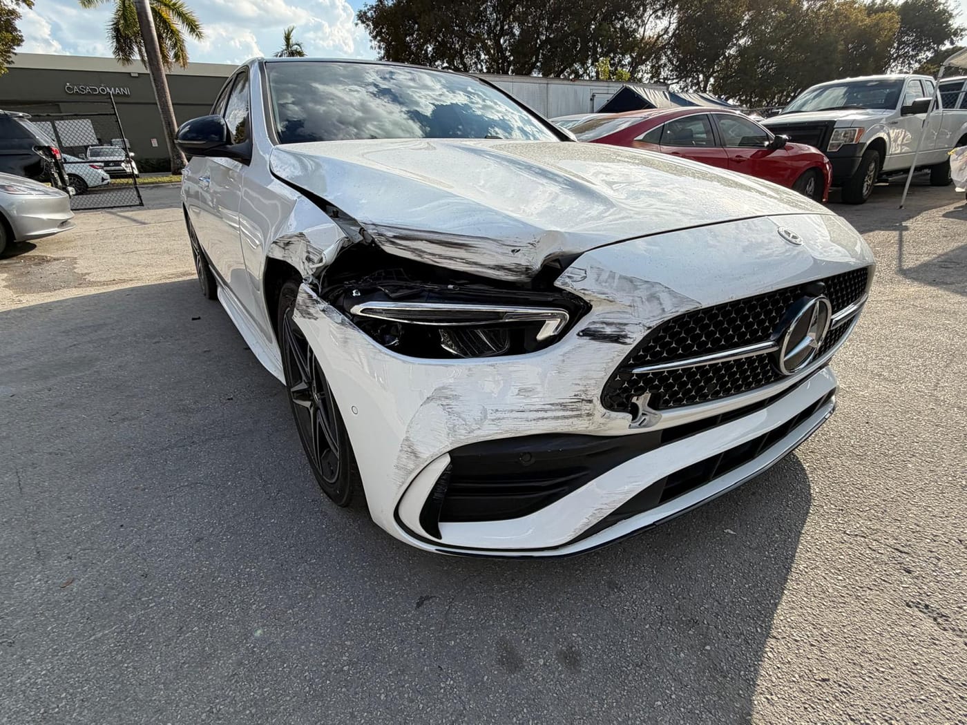 The same white Mercedes-Benz C-Class before repair, showing front-left collision damage